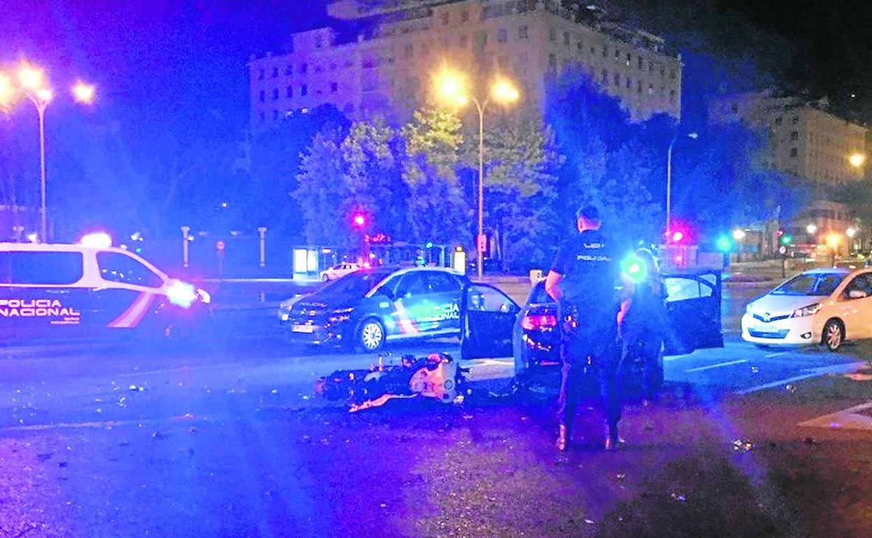 Una patrulla observa la moto de un joven de 23 años que murió el sábado en Madrid en una colisión con un coche en el Paseo de la Castellana.