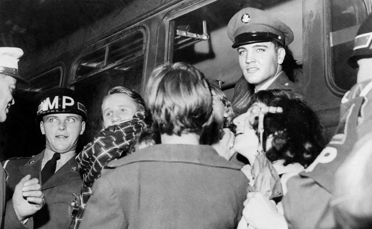 El cantante Elvis Presley, ataviado con indumentaria militar, rodeado de admiradoras, a su llegada a Friedberg (Alemania) para cumplir su servicio militar en el Ejército estadounidense.
