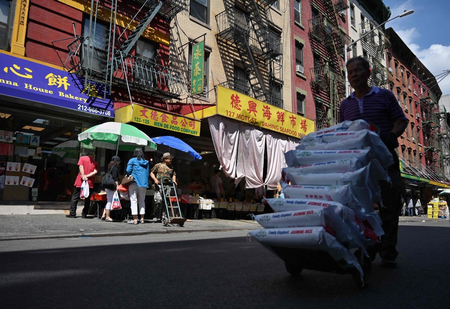Un hombre lleva bolsas de arroz por Chinatown en la ciudad de Nueva York. - Con una población estimada de 90,000 a 100,000 personas, Chinatown es el hogar de la mayor concentración de chinos en el hemisferio occidental.