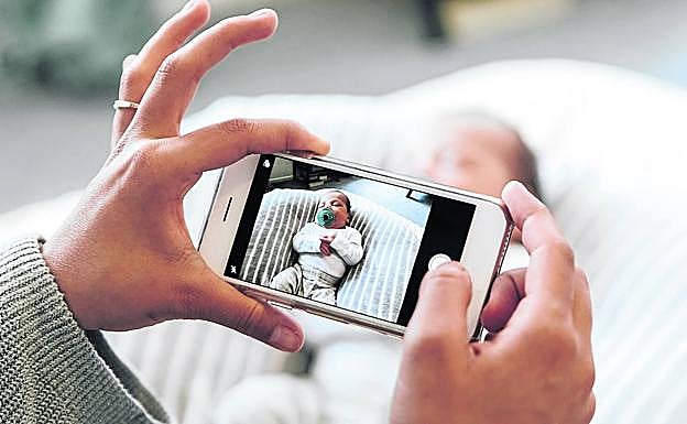Una madre fotografía con el móvill a su bebé mientras duerme.