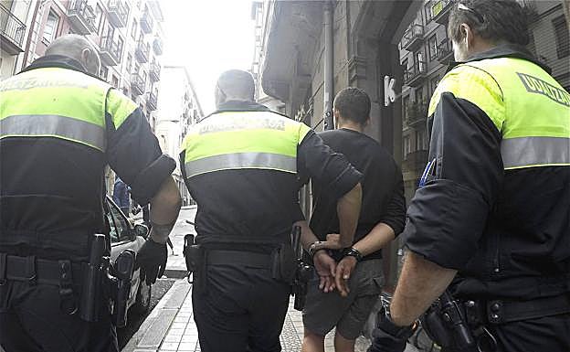 Tres agentes se llevan a uno de los detenidos.