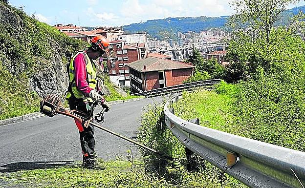 Un operario limpia los márgenes de la carretera.