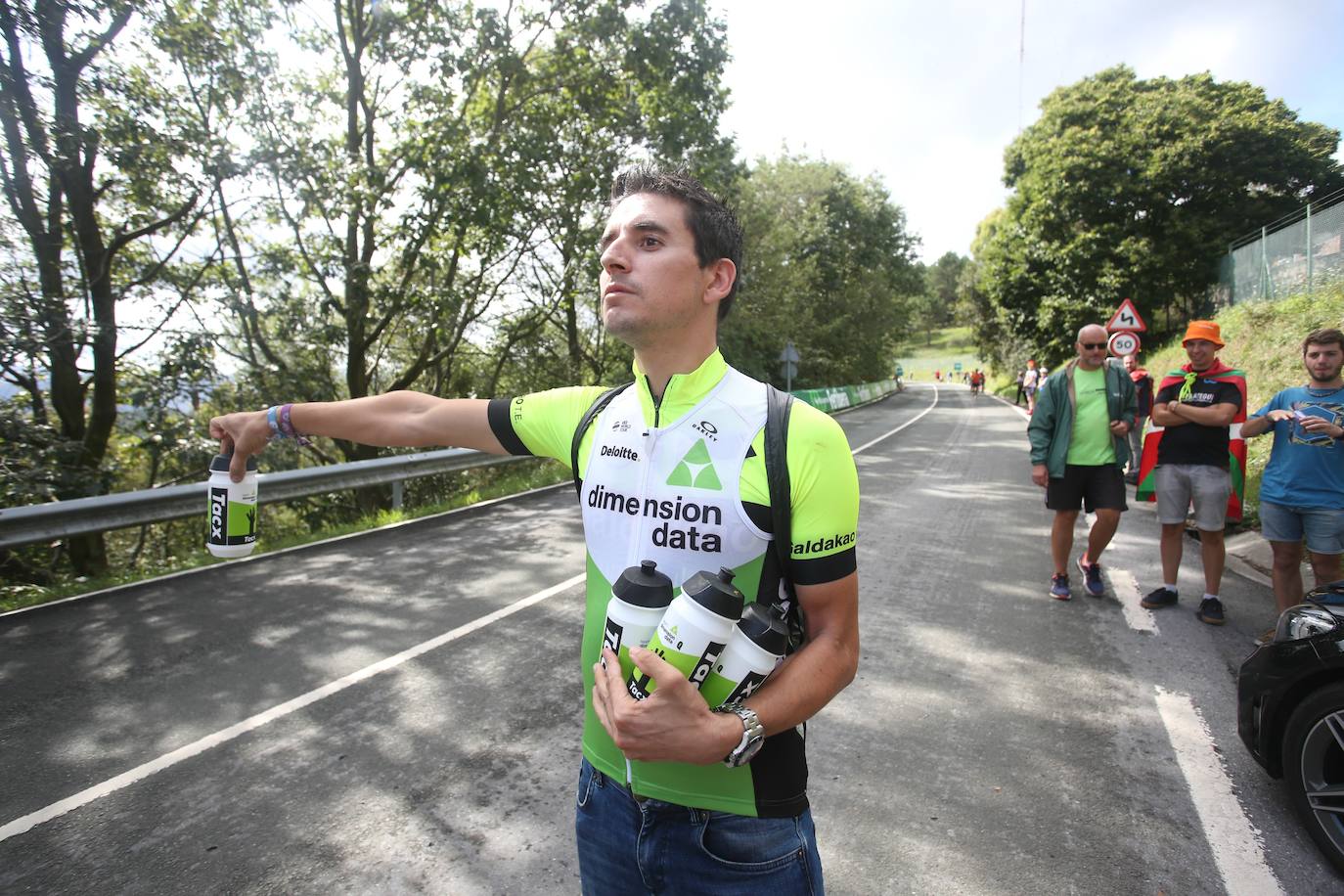 Igor Antón entrega botellines junto a los auxiliares del equipo Dimension Data.