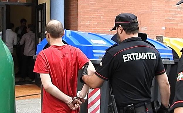 Un agente conduce a un detenido al piso en el que presuntamente cuatro hombres retuvieron y violaron a una mujer.