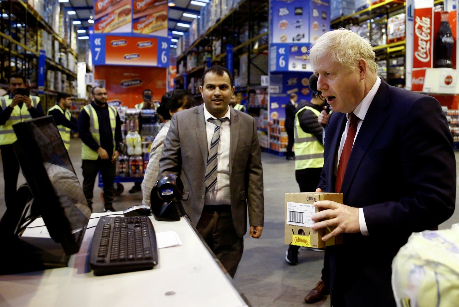 El primer ministro británico, Boris Johnson, reacciona mientras escanea un artículo durante una visita a Bestway Wholesale en Manchester, Gran Bretaña