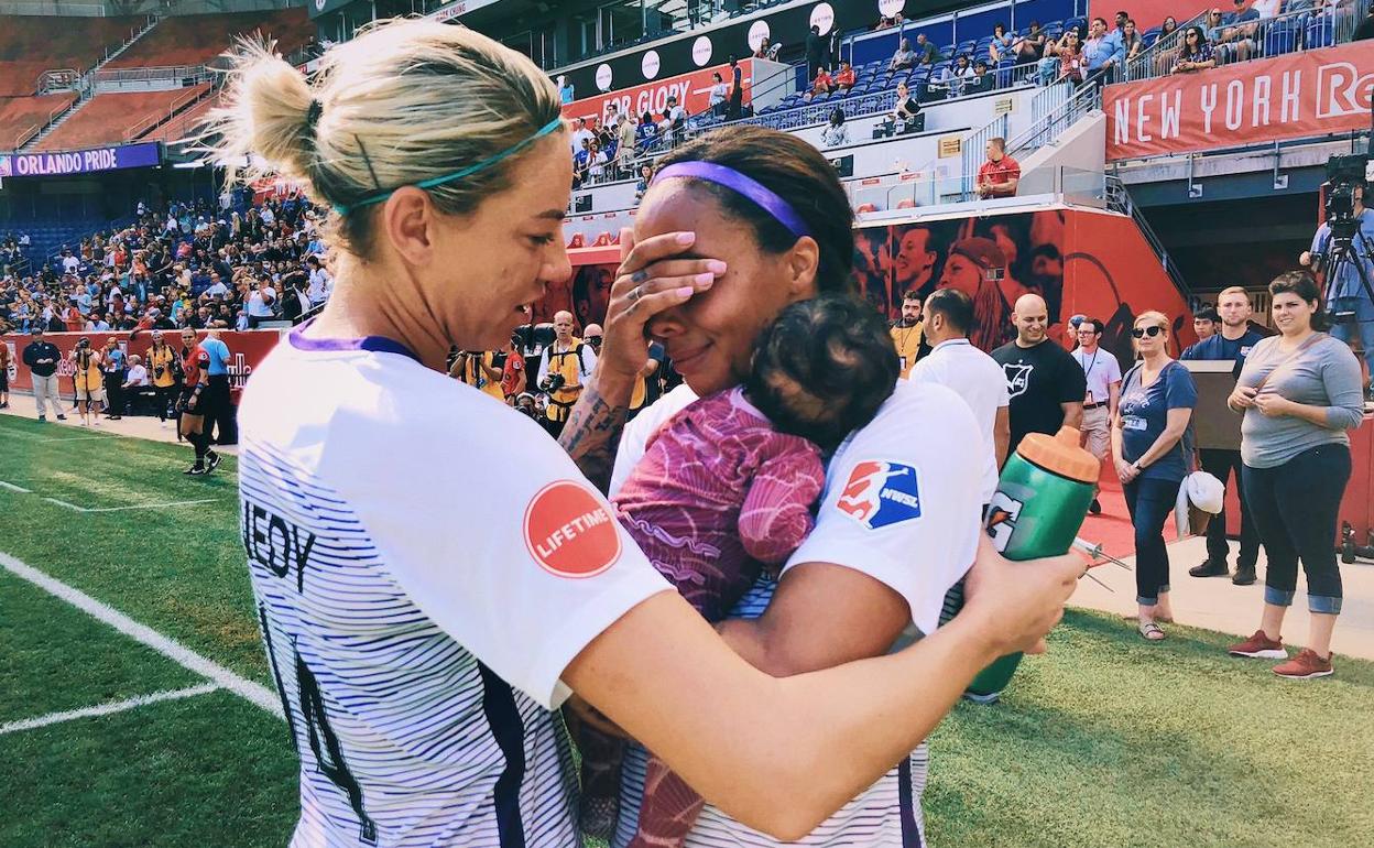La jugadora del Orlando Pride abraza a su hija emocionada mientras recibe el cariño de una de sus compañeras. 