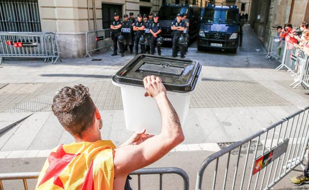 Un joven muestra una urna empleada el 1-O a los policías nacionales apostados ante la comisaría de la céntrica Via Laietana de Barcelona.