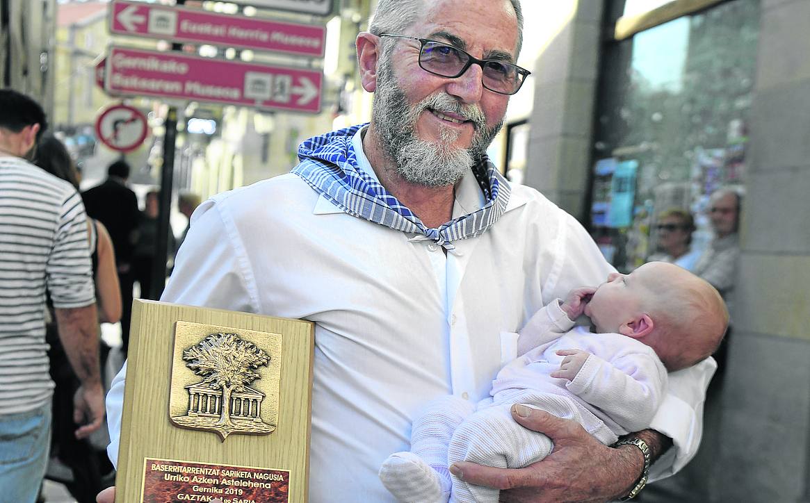 José Ramón Martínez posa con el trofeo al mejor queso en un brazo y su nieta en el otro.