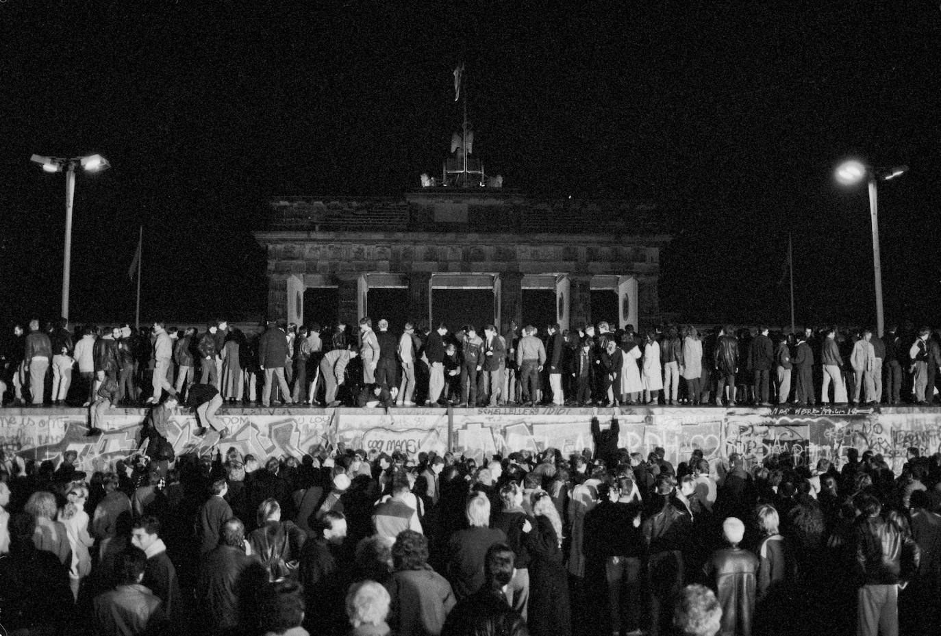 (5) Antes: Los ciudadanos de Alemania Oriental y Occidental celebran la apertura de la frontera de Alemania Oriental en Berlín mientras escalan el muro en la puerta de Brandenburgo.