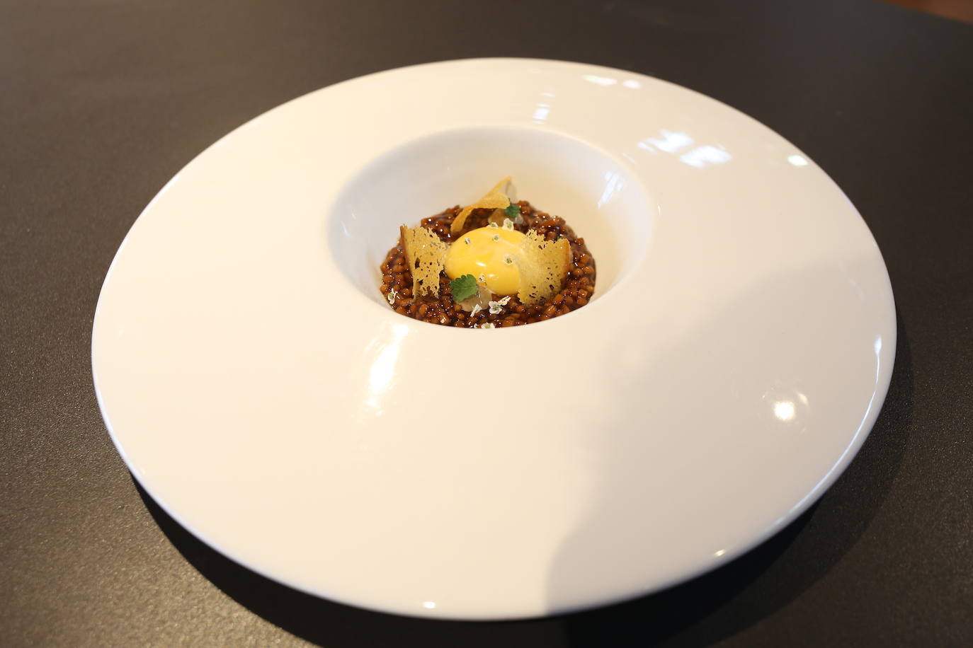 Menú 2 | Segundo plato: yema de huevo de caserío sobre estofado de trigo. Ingredientes: espaguetis troceados, yema de huevo, pimientos rojos, aceite, sal y tostas de pan