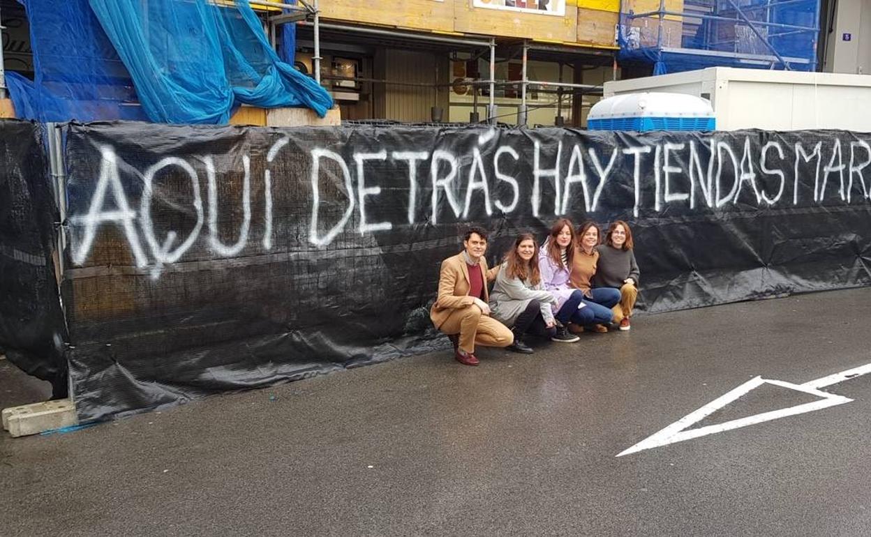 Los comerciantes afectados, junto al andamio que tapa sus tiendas. 