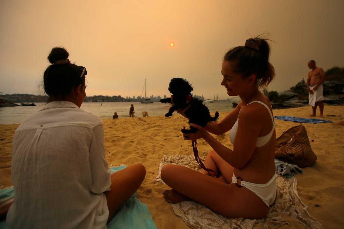 Bañistas en Milk Beach ven la neblina de humo de los incendios forestales en Nueva Gales del Sur, Australia