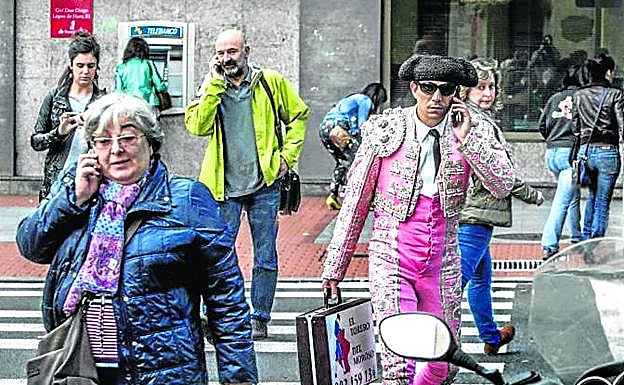 Peatones hablan por teléfono móvil mientras cruzan un paso de cebra. 