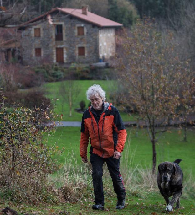 John Maguire y su perro pasean por el exterior de su casa.