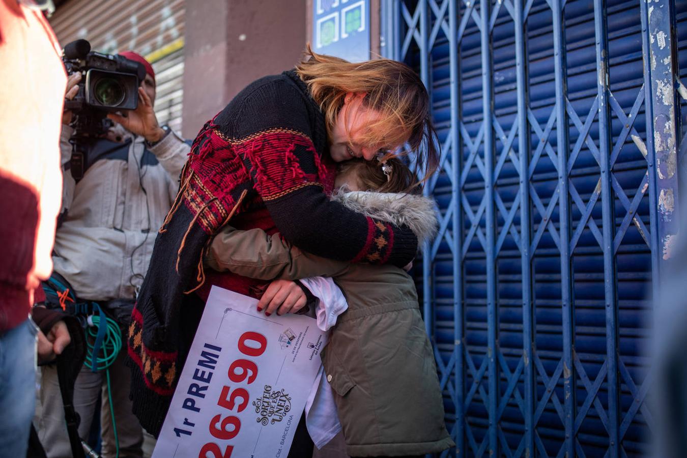 Una mujer abraza a su hija en Barcelona mientras sujeta el número que ha sido premiado con el Gordo.