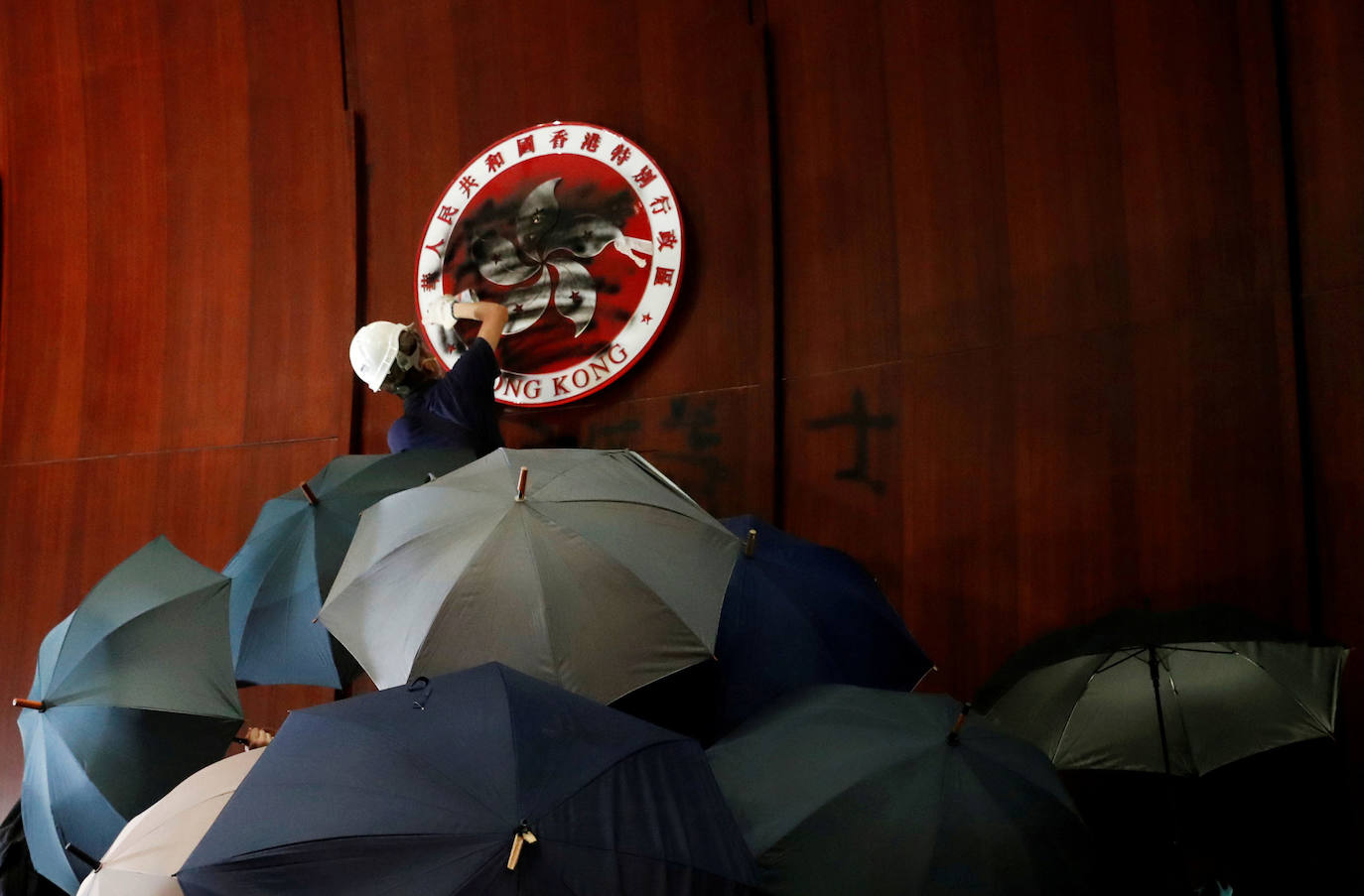 Hong Kong | Una persona rocía con pintura los escudos de armas de Hong Kong dentro de una cámara, después de que los manifestantes irrumpieram en el edificio del Consejo Legislativo, 1 de julio de 2019.