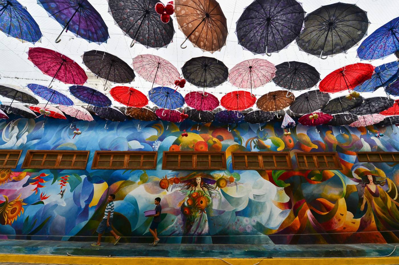 Dos niños caminan por una avenida céntrica cubierta de sombrillas en Cantarranas, Honduras. - Cantarranas, un pequeño municipio cerca de Tegucigalpa, se ha convertido en una exposición permanente de arte al aire libre. 