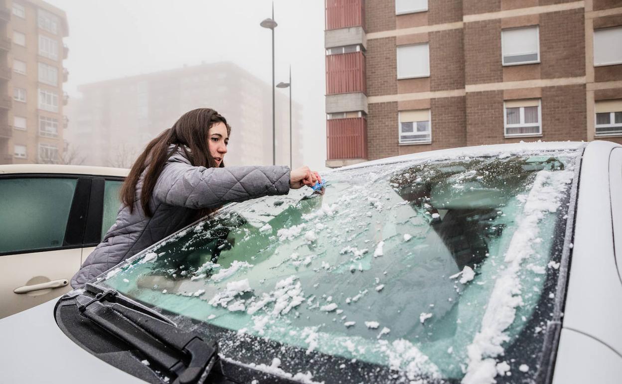 Una mujer retira el hielo del cristal de su coche en Judimendi. 