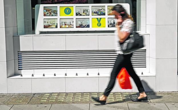 Una mujer camina junto a una agencia inmobiliaria del centro de Londres que incorporó elementos metálicos punzantes en su exterior.