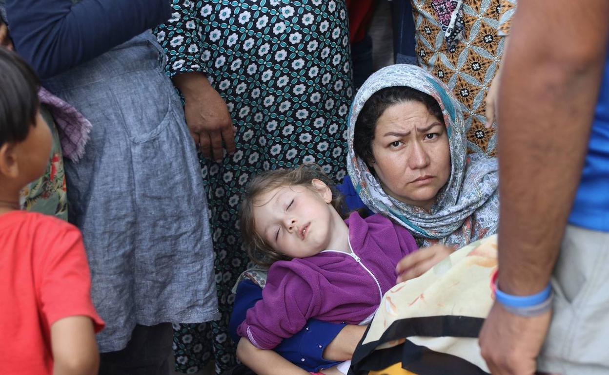 Emakume bat eta bere alaba janari banaketaren zain daude Moriako errefuxiatu eremuaren barruan, Greziako Lesbos uhartean.