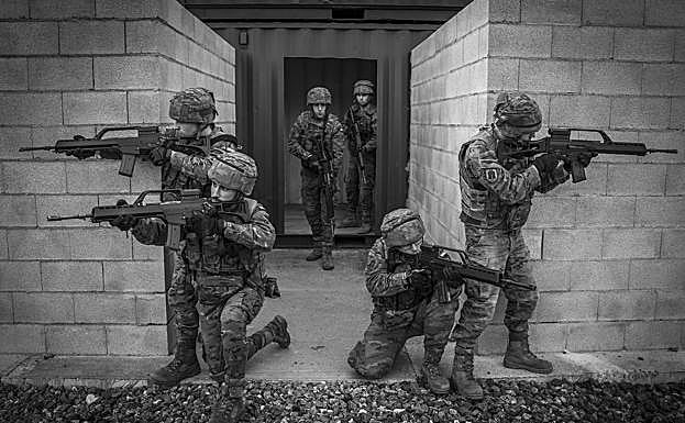 Imagen principal - Adiestramiento. Un pelotón ensaya técnicas de combate urbano en módulos de hormigón que recrean calles y casas. A continuación, la cantina, donde la cabo Arranz y el brigada Varela charlan durante un descanso. Este servicio y el rancho están subcontratados. Finalmente, un soldado se desliza haciendo rápel por la rampa de la torre multiusos mientras le sujeta su instructor.