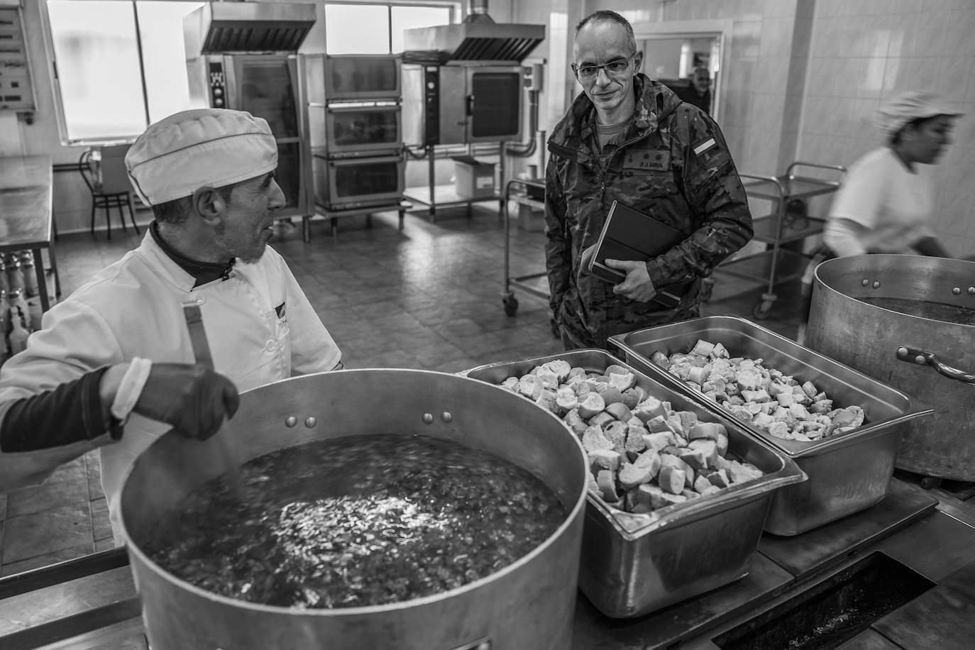 Una subcontrata se encarga de elaborar el rancho que se sirve a las tres de la tarde. La comida, fuera del horario laboral, corre por cuenta de tropa y oficiales, aunque el precio está subvencionado y es de apenas dos euros. El día del reportaje, el menú consistía en lentejas de primer plato y a escoger entre trucha y sanjocobo de segundo. En la imagen, un teniente coronel conversa con el cocinero mientras prepara la comida de la noche.