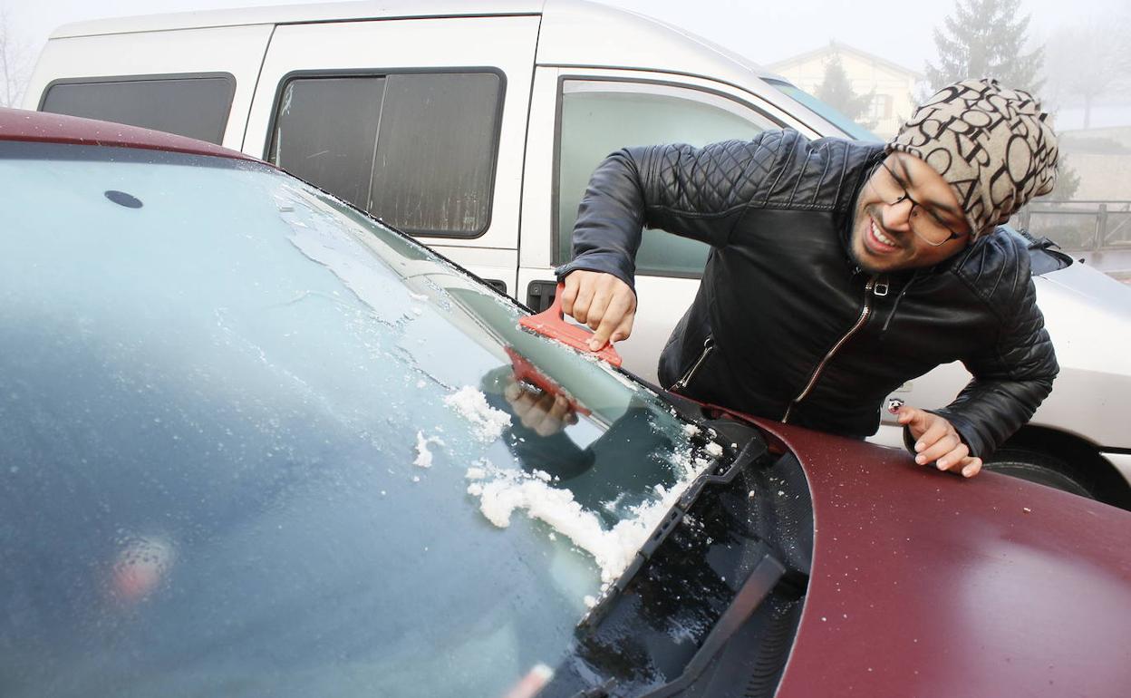 Un joven retira el hielo de su vehículo tras la helada de hace unos días. 