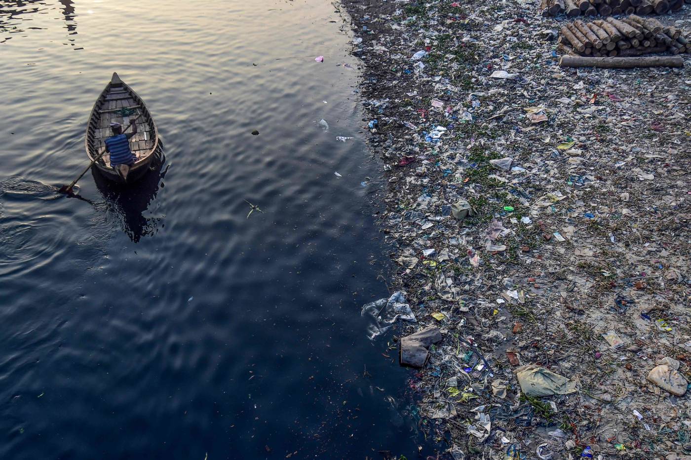 Un hombre rema en un bote mientras las bolsas de plástico flotan en la superficie del agua del río Buriganga en Dhaka. El tribunal superior de Bangladesh ordenó el cierre de 231 fábricas que han contribuido a que el río principal de Dhaka se convierta en uno de los más contaminados del mundo. 