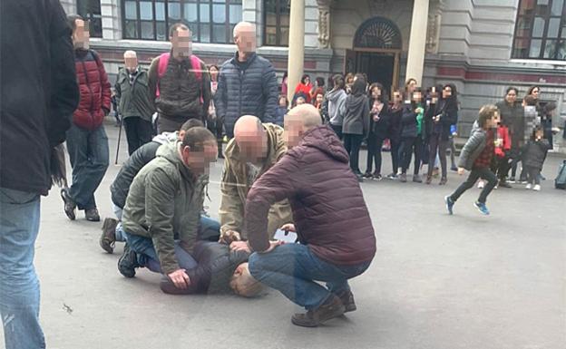 El sospechoso, inmovilizado en el suelo por cuatro padres, a la espera de la llegada de la Policía.