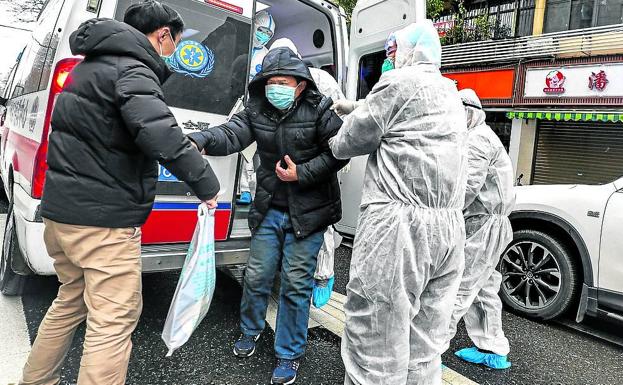 Imagen principal - En China se extienden los controles en los servicios de transporte y vehículos privados. Unos padres colocan la mascarilla a su hijo en una calle de Pekín. Un hombre baja de una ambulancia en Wuhan.