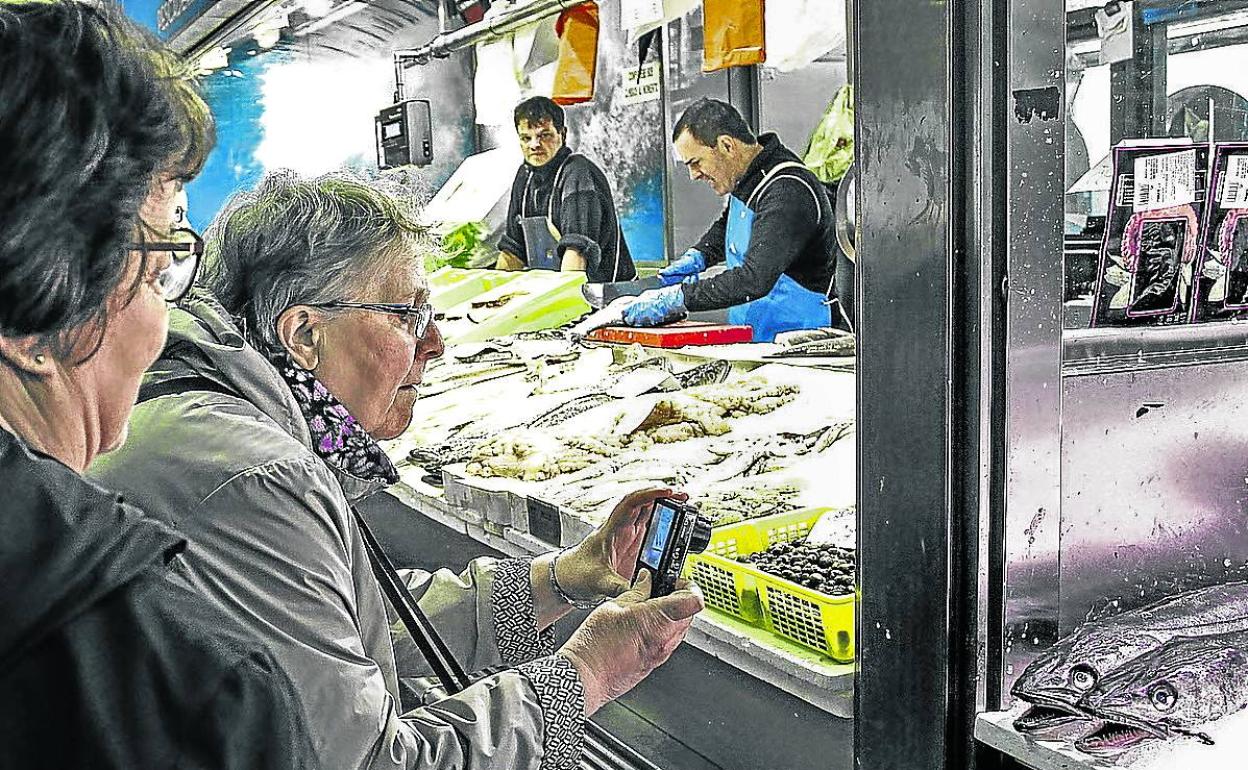 Una mujer fotografía el mostrador de una pescadería en el Mercado de La Ribera.