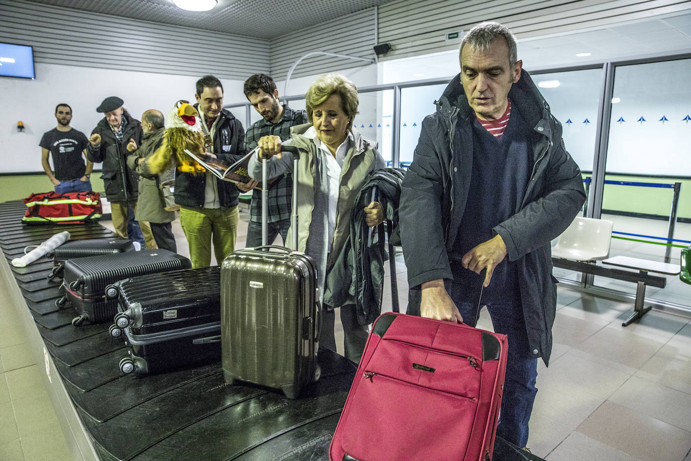 El actor Eloi Beato y Amparo Basterra, de la Real Sociedad Bascongada de Amigos del País, retiran su equipaje de la cinta. A su lado, el escritor Álvaro Arbina sujeta un libro ante el librero Carlos Villar, de Astrolibros.