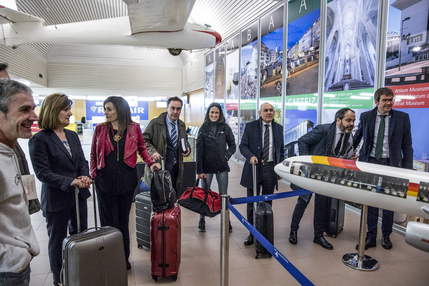 Los protagonistas del reportaje observan la maqueta de una aeronave, situada en la terminal de Foronda, junto a carteles promocionales de Vitoria y Álava.