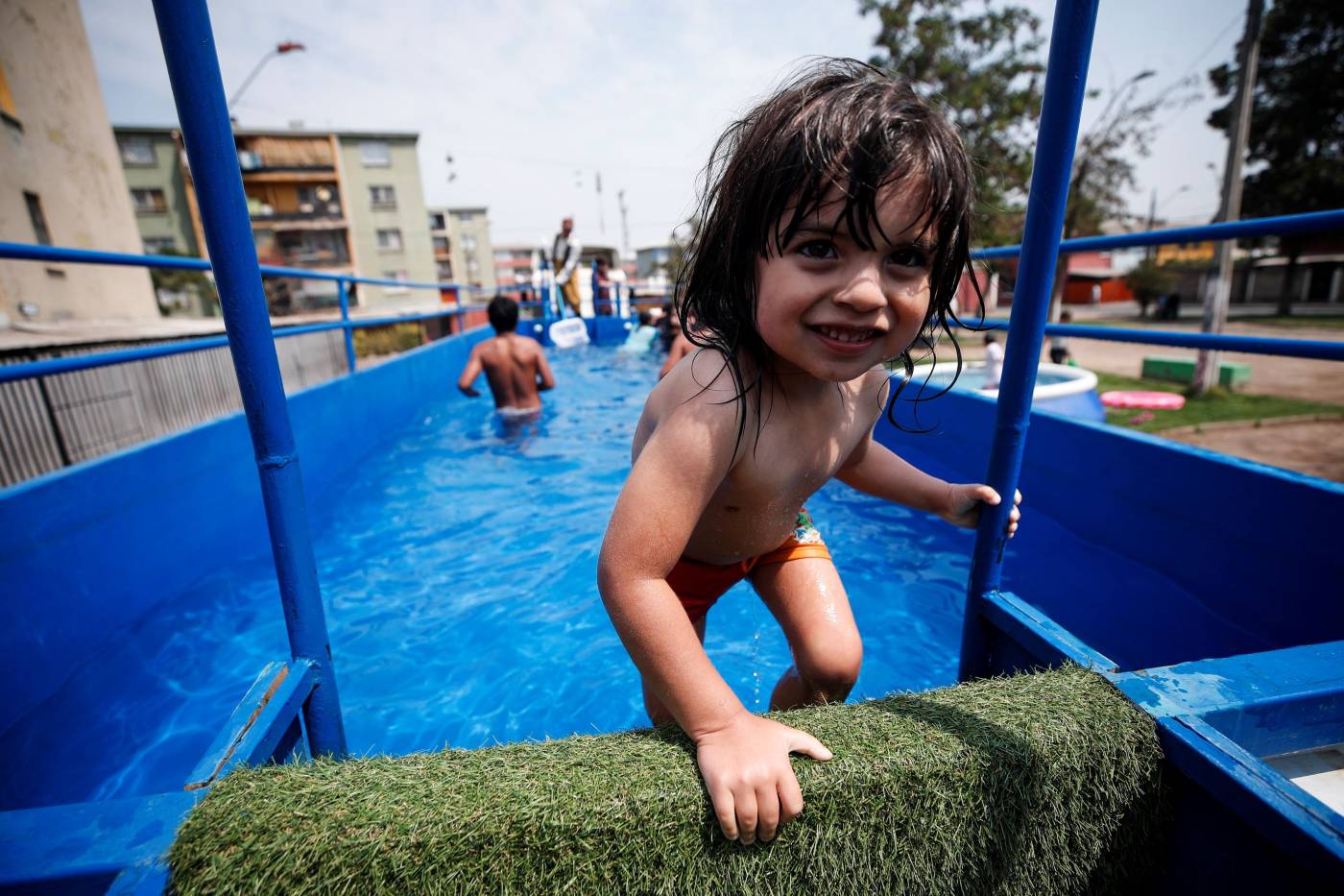 Niños juegan en una piscina móvil construida en un camión que recorre algunas de las zonas más desfavorecidas de Santiago (Chile), para permitir a los vecinos refrescarse y soportar las altas temperaturas. 