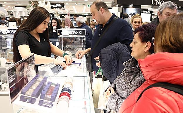 Una dependienta atiende a varios clientes en un centro comercial. 