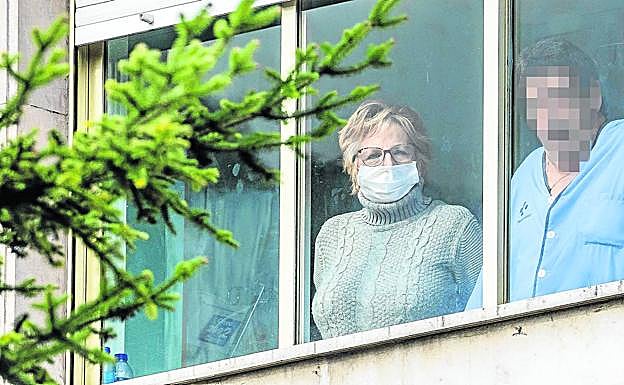 Un paciente y su acompañante, ésta con mascarilla, se asoman a una ventana del hospital Txagorritxu. 