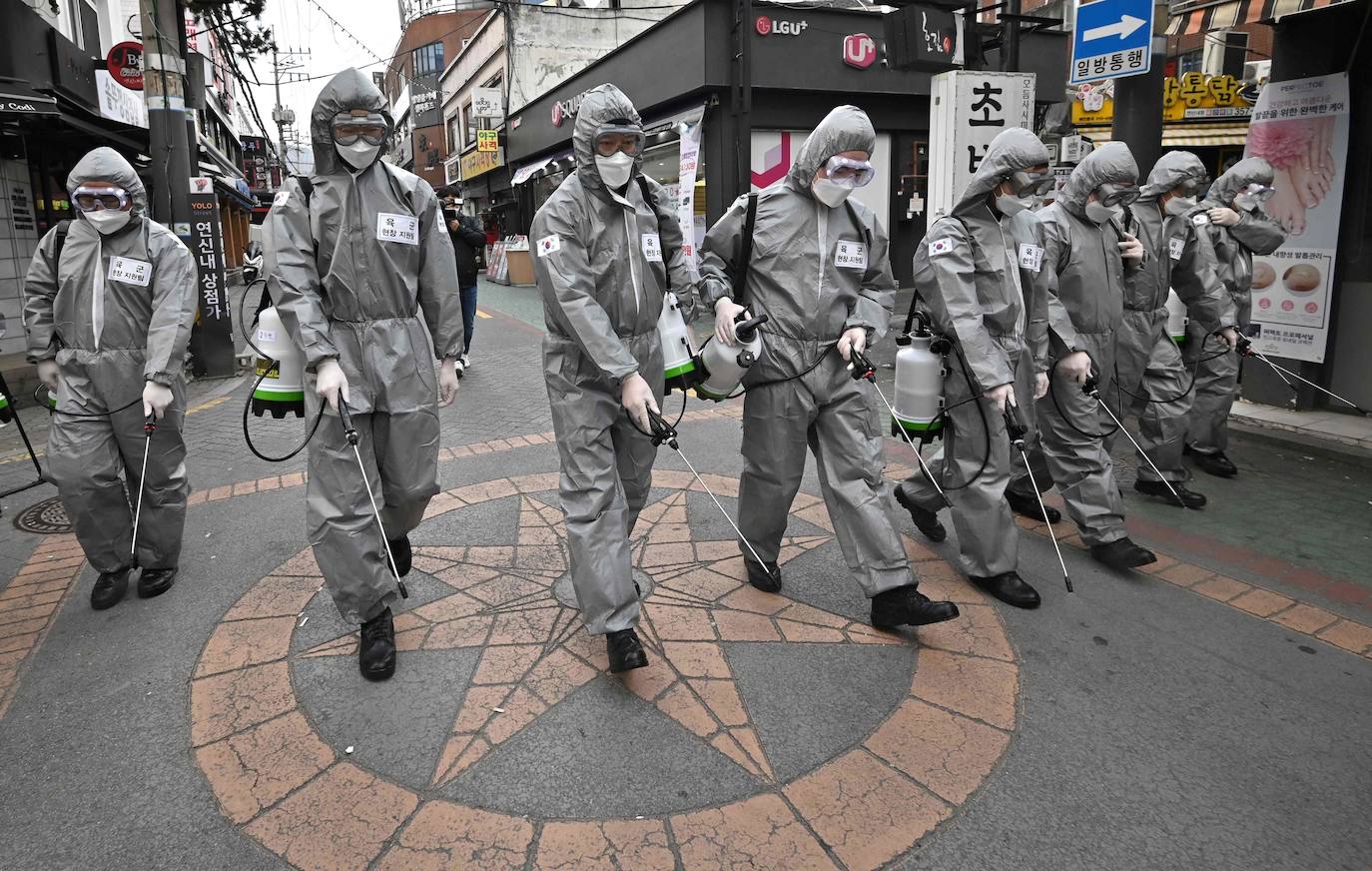 Soldados surcoreanos fumigan con desinfectante en aerosol para ayudar a prevenir la propagación del coronavirus en un distrito comercial de Seúl.