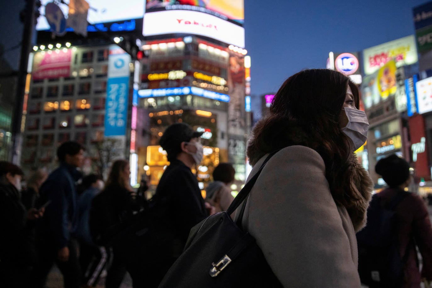 Una mujer con una máscara protectora en el cruce en el distrito comercial de Shibuya en Tokio.