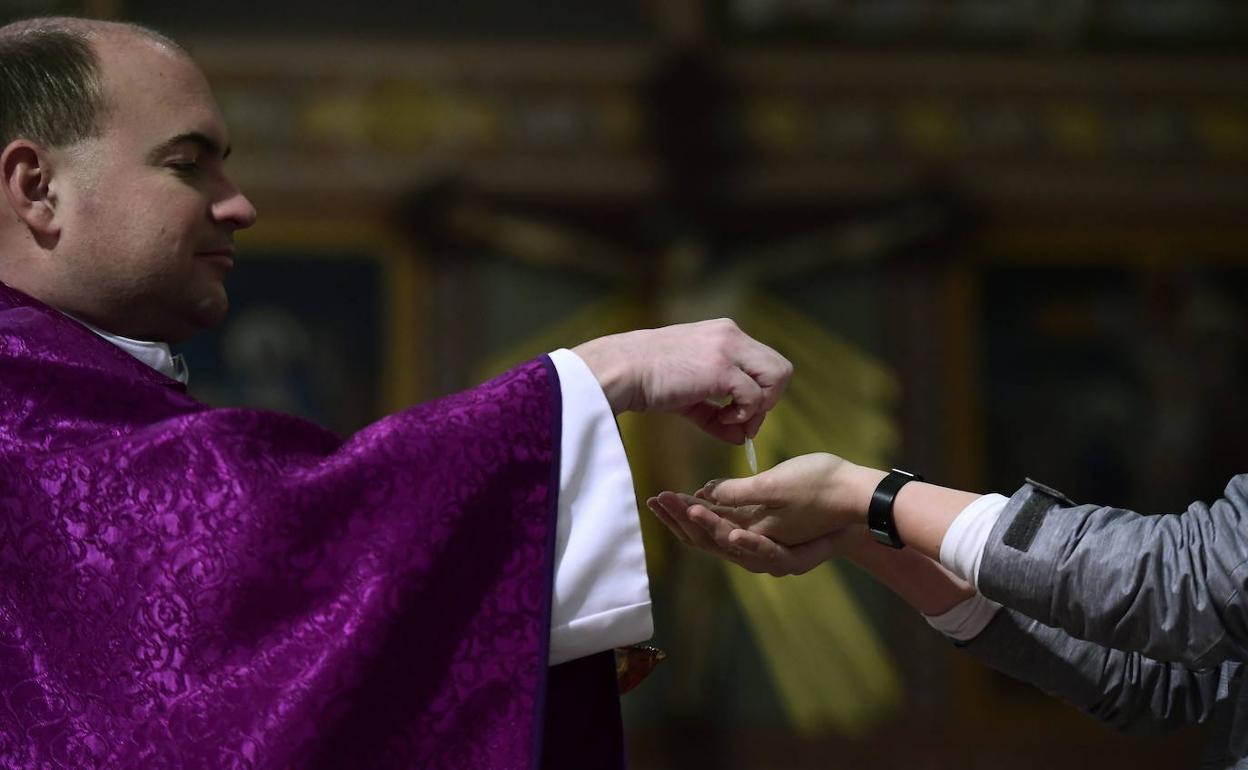 Un sacerdote reparte la Sagrada Comunión en mano