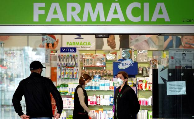 La empleada de una farmacia atiende a un cliente guardando la distancia recomendada por las autoridades.