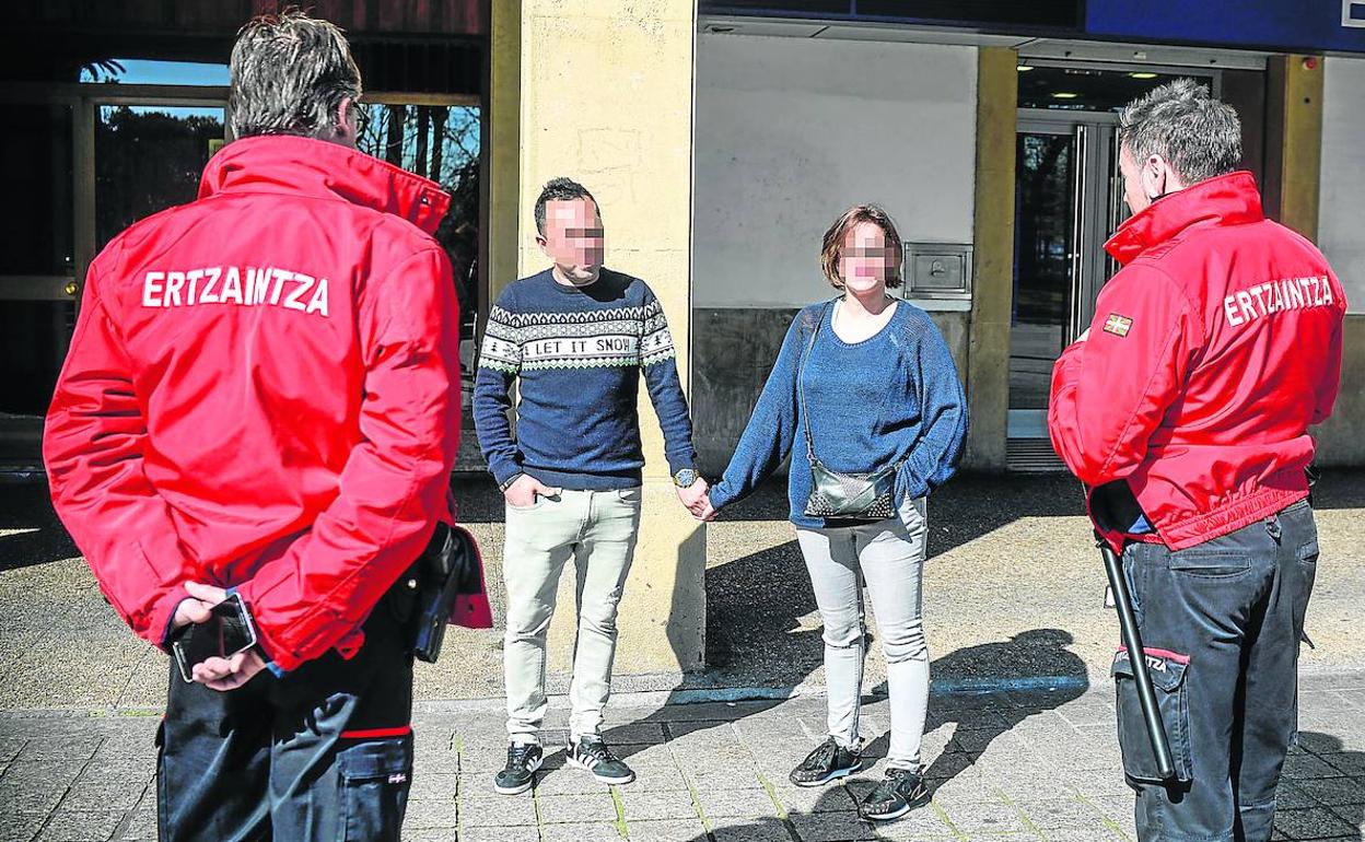 Dos ertzainas recuerdan a una pareja la obligación de limitar los movimientos a causas de fuerza mayor y caminar separados. 