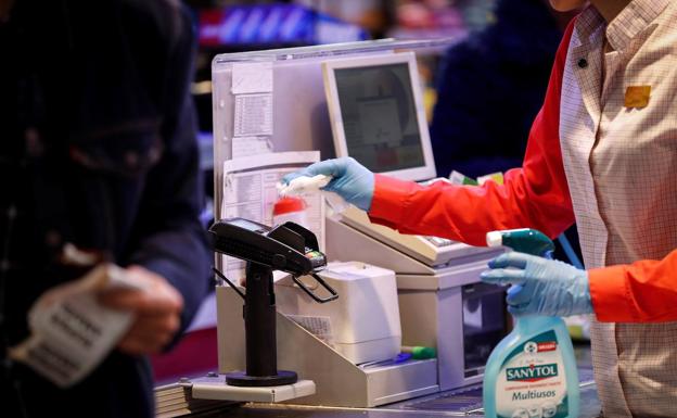 La empleada de un supermercado desinfecta su lugar de trabajo.