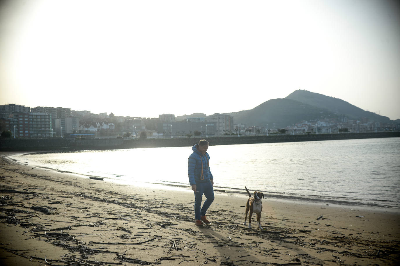 Un hombre y su perro, en la playa de Ereaga.