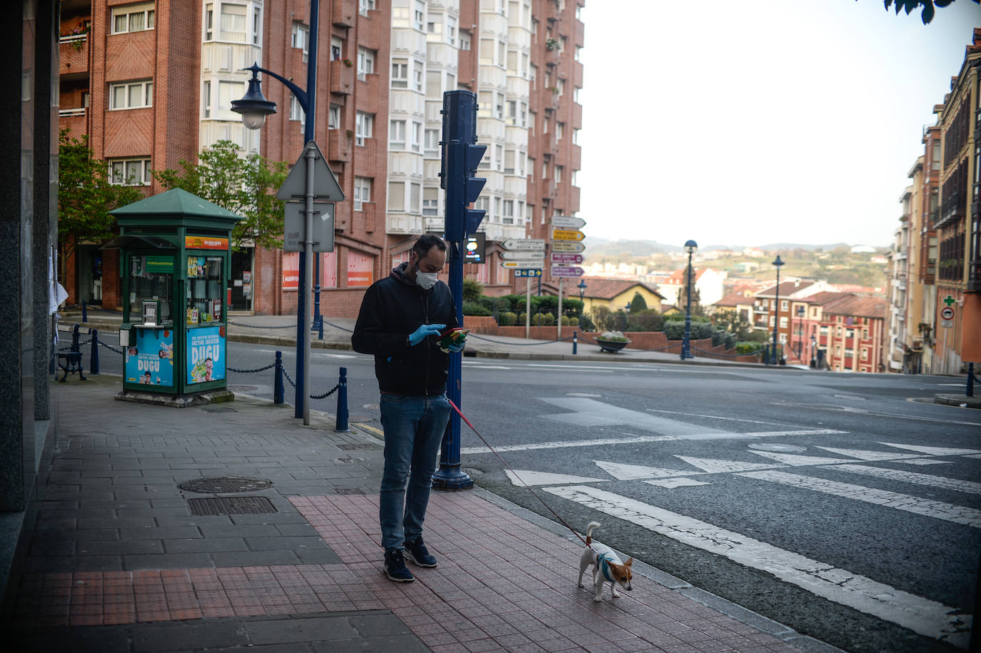 Un hombre protegido con una mascarilla pasea a su perro en Portugalete.