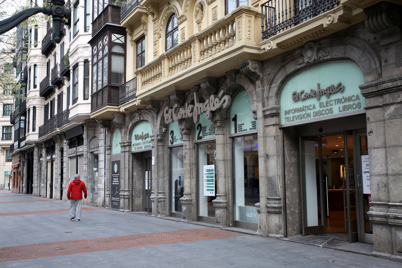 Un hombre pasea por la Gran Vía de Bilbao, frente a El Corte Inglés de aparatos electrónicos.