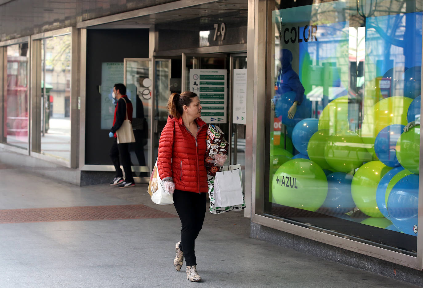 Una mujer pasea cargada con bolsas frente a El Corte Inglés de Bilbao.