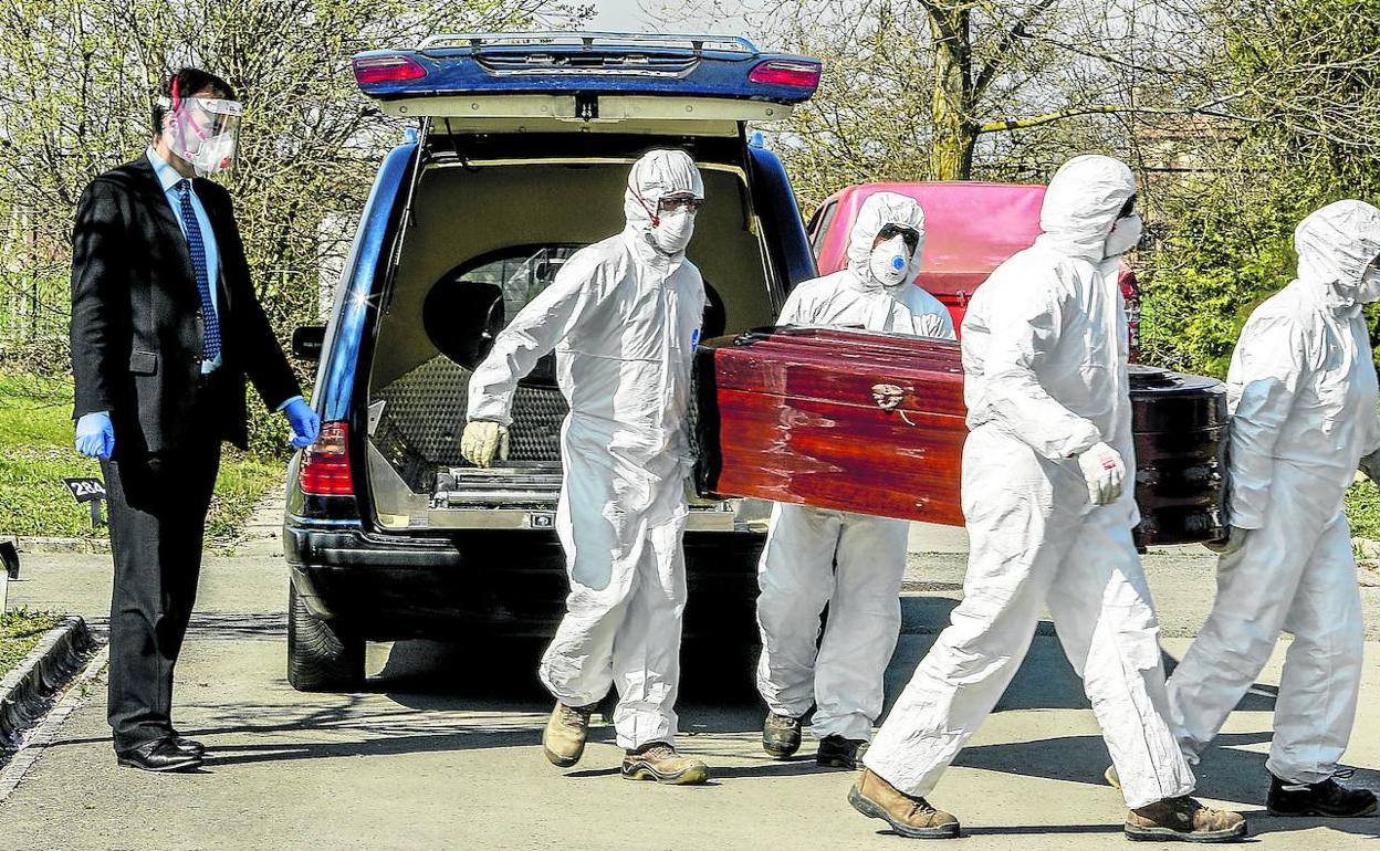 Empleados de una funeraria local trasladan un féretro para su enterramiento en El Salvador. 