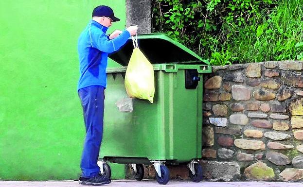 Eduardo sale a un contenedor para echar la basura.