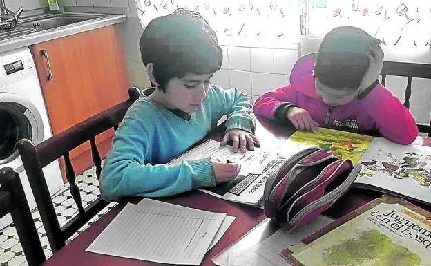 Evan y su hermano Diogo, de 6 y 9 años, realizan sus tareas en la mesa de la cocina.