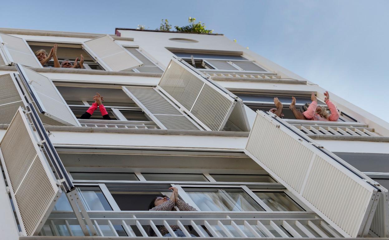 Varias personas salen a balcones y ventanas de sus casas para aplaudir a los sanitarios.